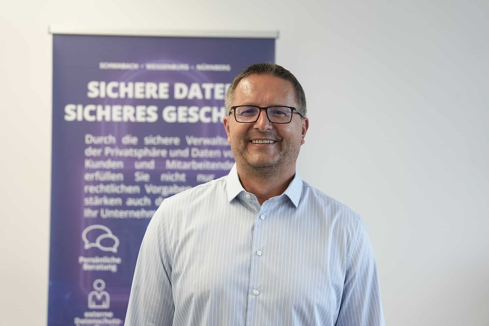 Christian Schermer, Geschäftsführer der BES Systemhaus GmbH, vor dem Roll-up „Sichere Daten, sicheres Geschäft“